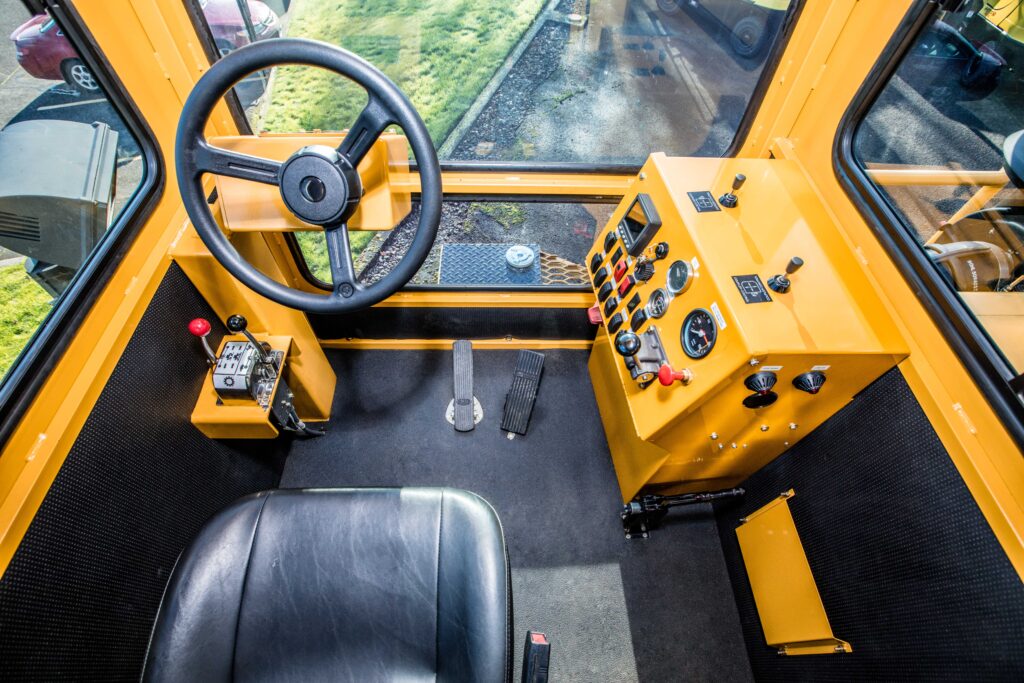Interior of a Trackmobile railcar mover operator cab showing ergonomic control console, operator seat, visibility windows, and railcar control systems