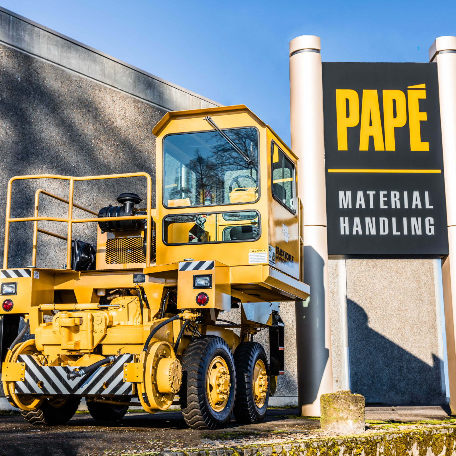 Trackmobile mobile railcar mover positioned on rail in front of Papé Material Handling facility, used for on-site industrial railcar switching